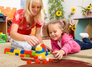 Nanny and child are playing with bricks